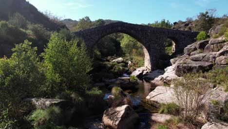 Volando-Sobre-El-Antiguo-Puente-De-Piedra-Sobre-El-Hermoso-Río