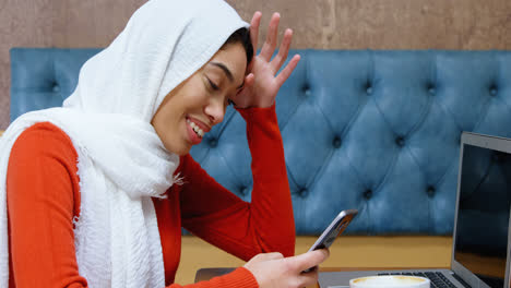 Woman-using-mobile-phone-in-cafeteria-4k