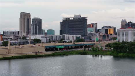 aerial view of orlando downtown with traffic om highway during cloudy day in usa. descending drone wide shot.