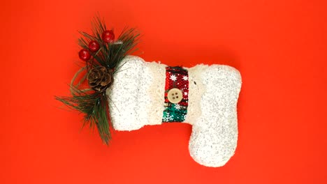 juguete de navidad con forma de medias o botas de año nuevo, gira sobre fondo rojo.