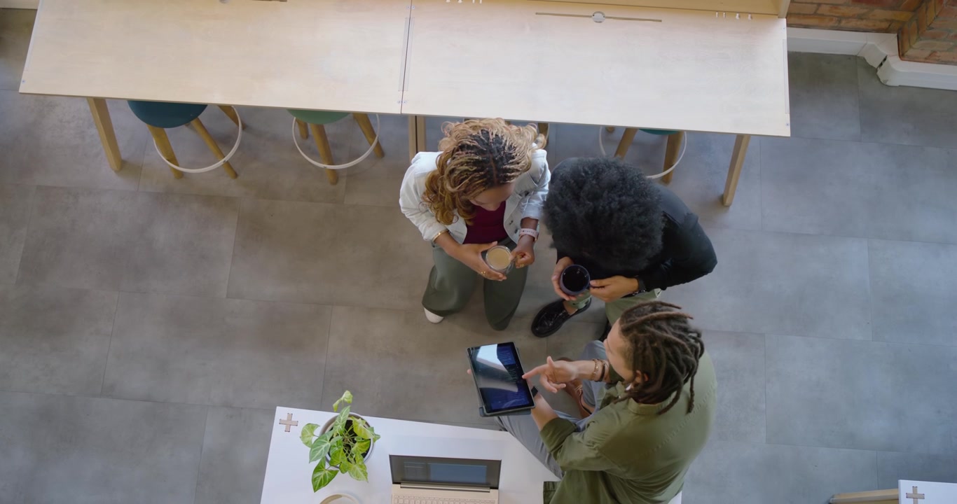 African American team leaning at desk, tablet tilting, swiping and reviewing project on laptop
