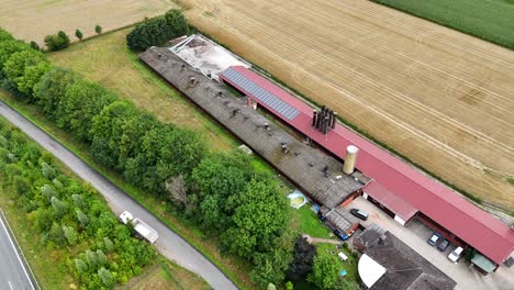 red barn building with solar panels on american farmstead. driving cars on suburb intersection road on summer. aerial top down shot. quiet and idyllic rural landscape scene