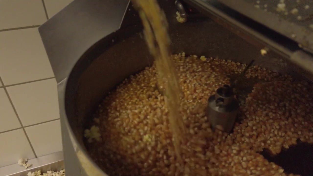 Rekaman gerak lambat biji jagung dituang ke dalam mesin popcorn