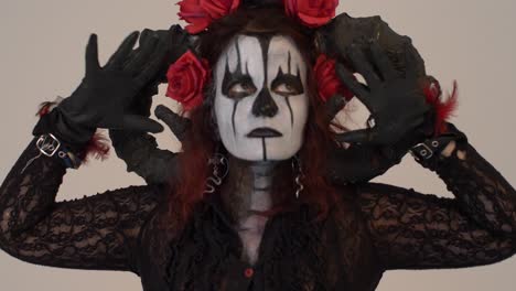 catrina cosplay girl moving her hands infront of her face with a light background, medium close up