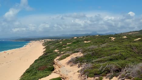 Flying-over-the-sea,-beach-and-sand-dune-in-Sardaigna,-dunes-of-Piscinas