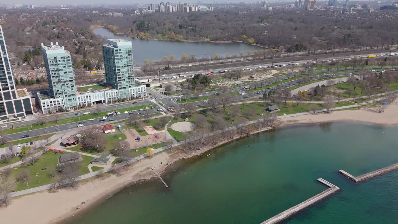 Traffic scene on expressway road in suburb of Toronto City, Canada. Sunny day at High Park with Lakeshore Boulevard. Tranquil Lake Ontario in distance. Aerial establishing shot. Sandy beach at bay.