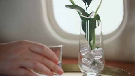 mano poniendo vaso de agua en la mesa de cerca. pasajero del avión descansando en el viaje