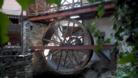 antigua rueda de molino de agua en exhibición en una cabaña antigua renovada con hiedra