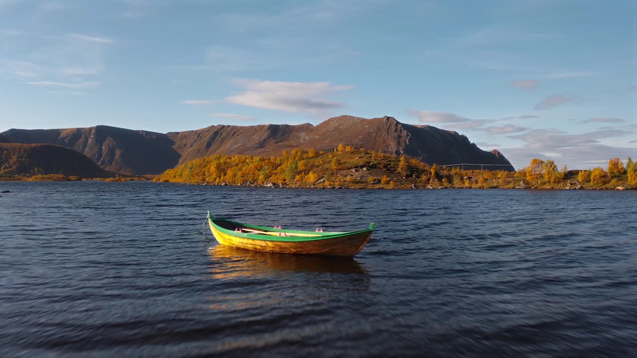 Peaceful autumn landscape with a small boat floating on calm water surrounded by mountains