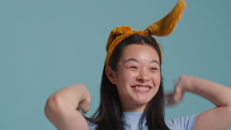 Young-Woman-In-Front-Of-Blue-Studio-Background-Dressing-Up-And-Posing-For-Photo-Booth-Style-Portraits-2