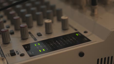 push in to reveal an audio meter spiking on a mixing board