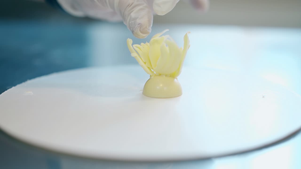 il dolciatore attacca un piccolo petalo al fiore di cioccolato bianco