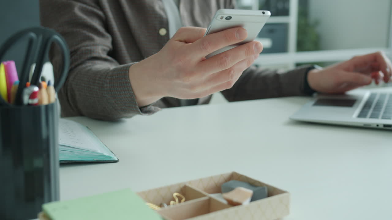 Person Working on Laptop and Smartphone at Desk
