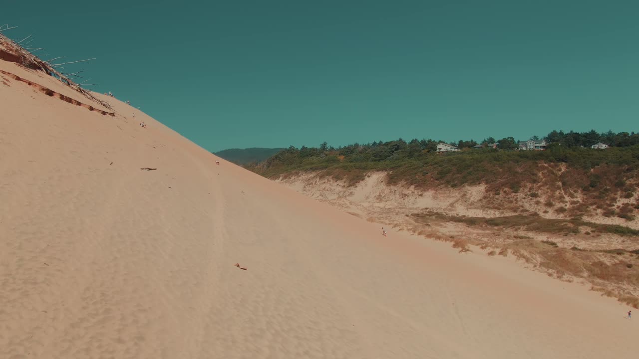 4k Aerial sand dune with people and green hills on background Drone dolly in