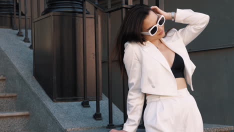 stylish woman in white pantsuit on city stairs