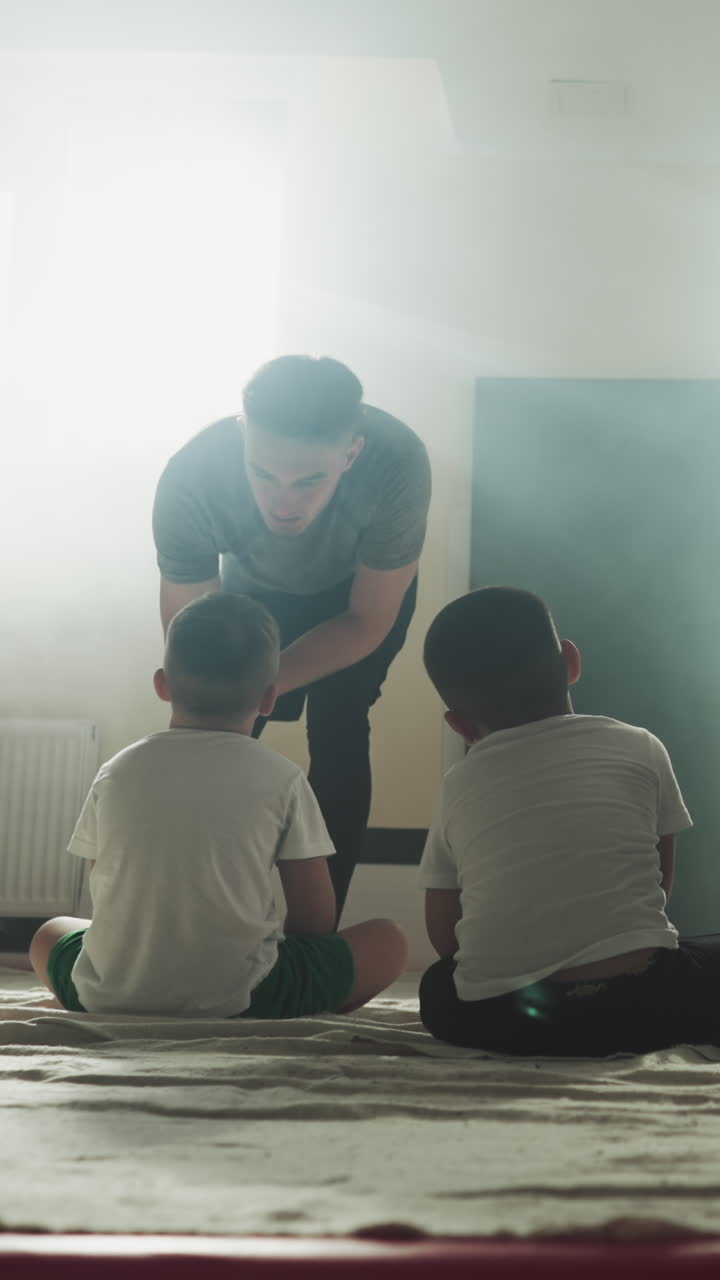 el entrenador regaña al mal estudiante en el club de artes marciales. los niños pequeños escuchan al instructor profesional sentado en el suelo en el gimnasio en cámara lenta. lección de combate