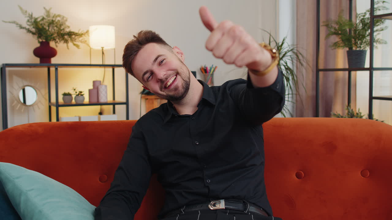 joven feliz mirando con aprobación a la cámara mostrando los pulgares hacia arriba, como un signo positivo, buenas noticias