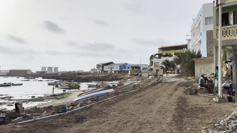 coastal view in sal rei, cape verde, shows colorful boats along the shore, local buildings, and people working near the water. captures the charm of daily life in this island community