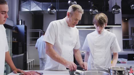 professional caucasian male chef wearing chefs whites in a restaurant kitchen teaching