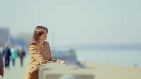 beautiful young woman is standing by the fence and enjoying the view. sunny spring day. circular motion of the camera.