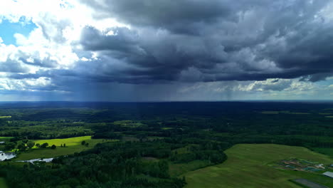 aerial view of a stormy landscape with rain falling over forests and fields