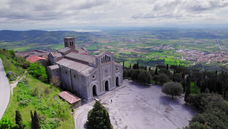 Aerial-pan-of-old-church-in-town-of-Cortona-on-hill-in-cloudy-Tuscany
