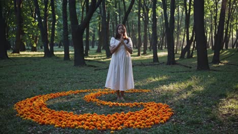 young woman in a flowing white dress performing a spiritual ritual surrounded by vibrant orange flowers, connecting with nature in a serene forest setting