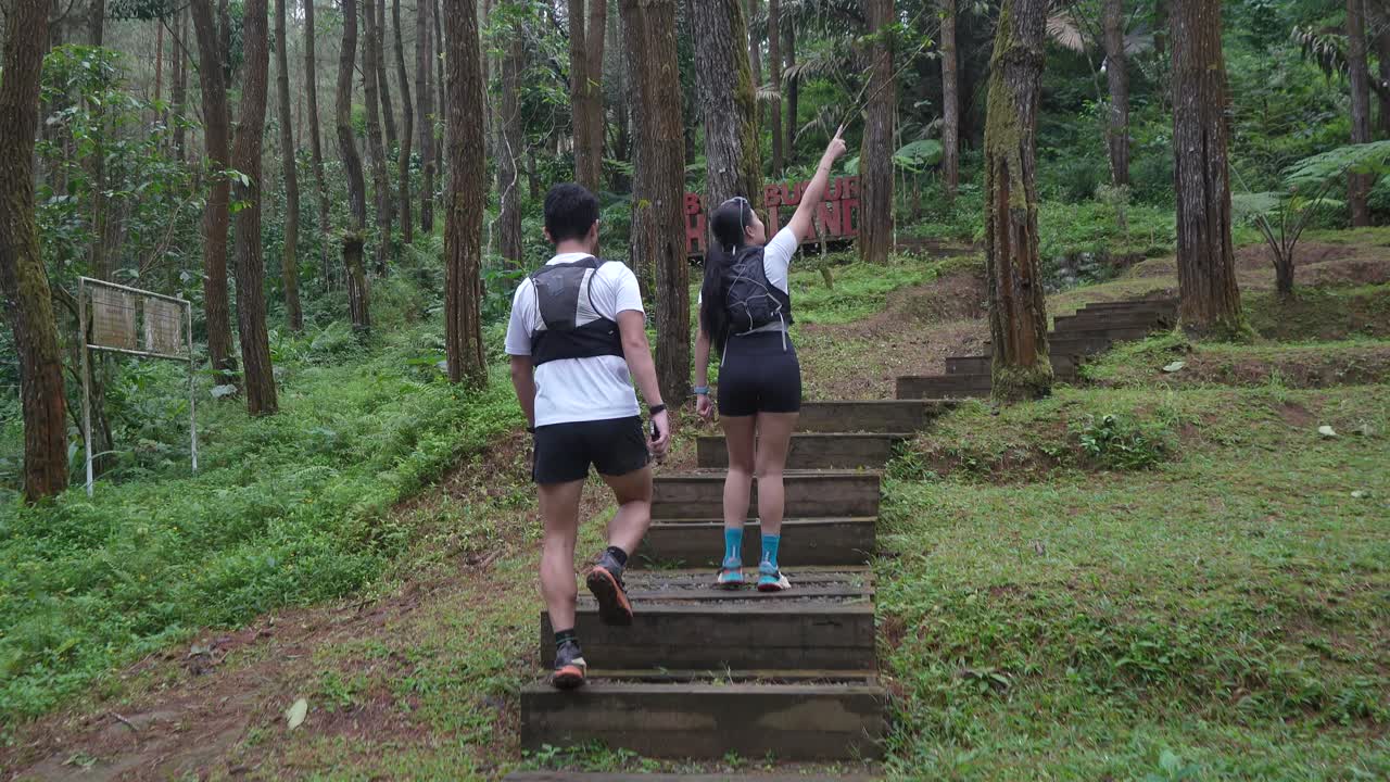 Asian couple walking on forest trail path during outdoor adventure in Indonesia