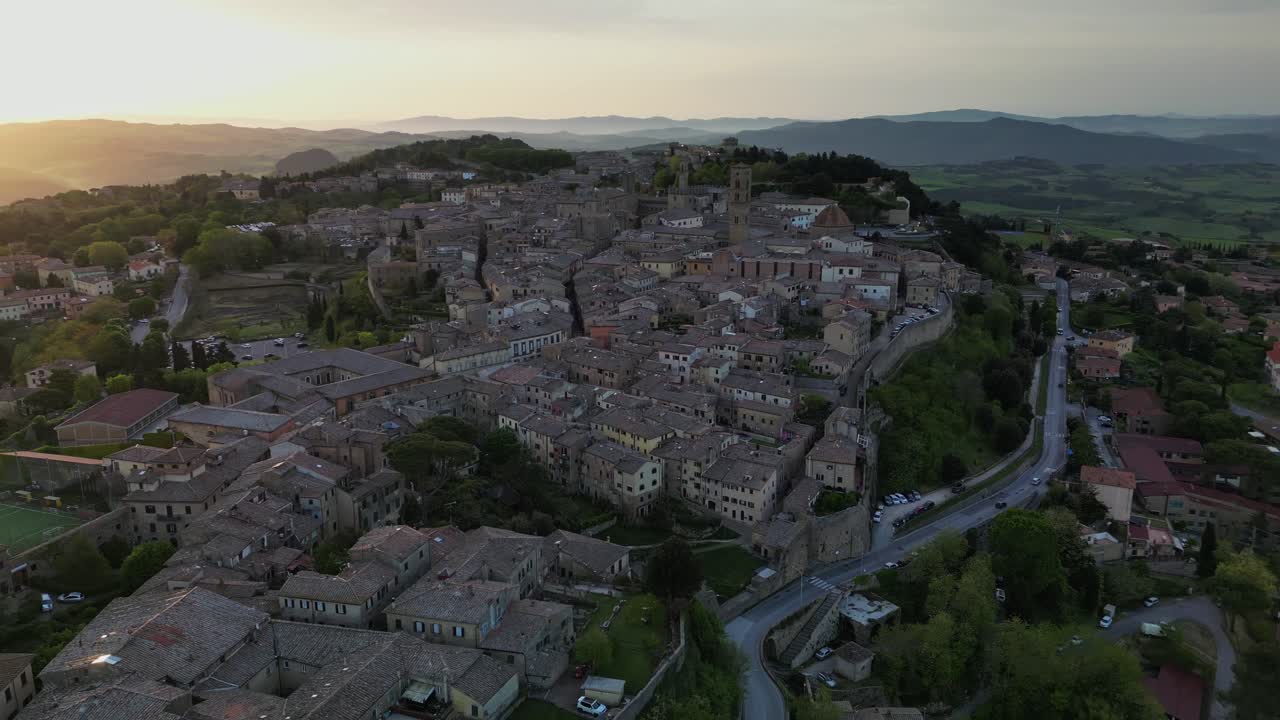 Vista drone all'alba di Volterra con architettura medievale, mura cittadine e le dolci colline toscane nella morbida luce del mattino