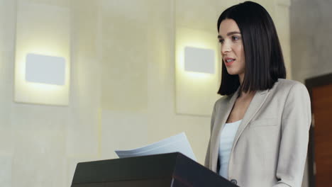 close-up view of caucasian businesswoman speaker on a podium wearing formal clothes and talking in a conference room