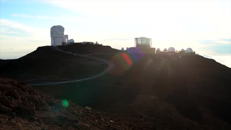 setting sun behind haleakala observatory on maui with sun flares