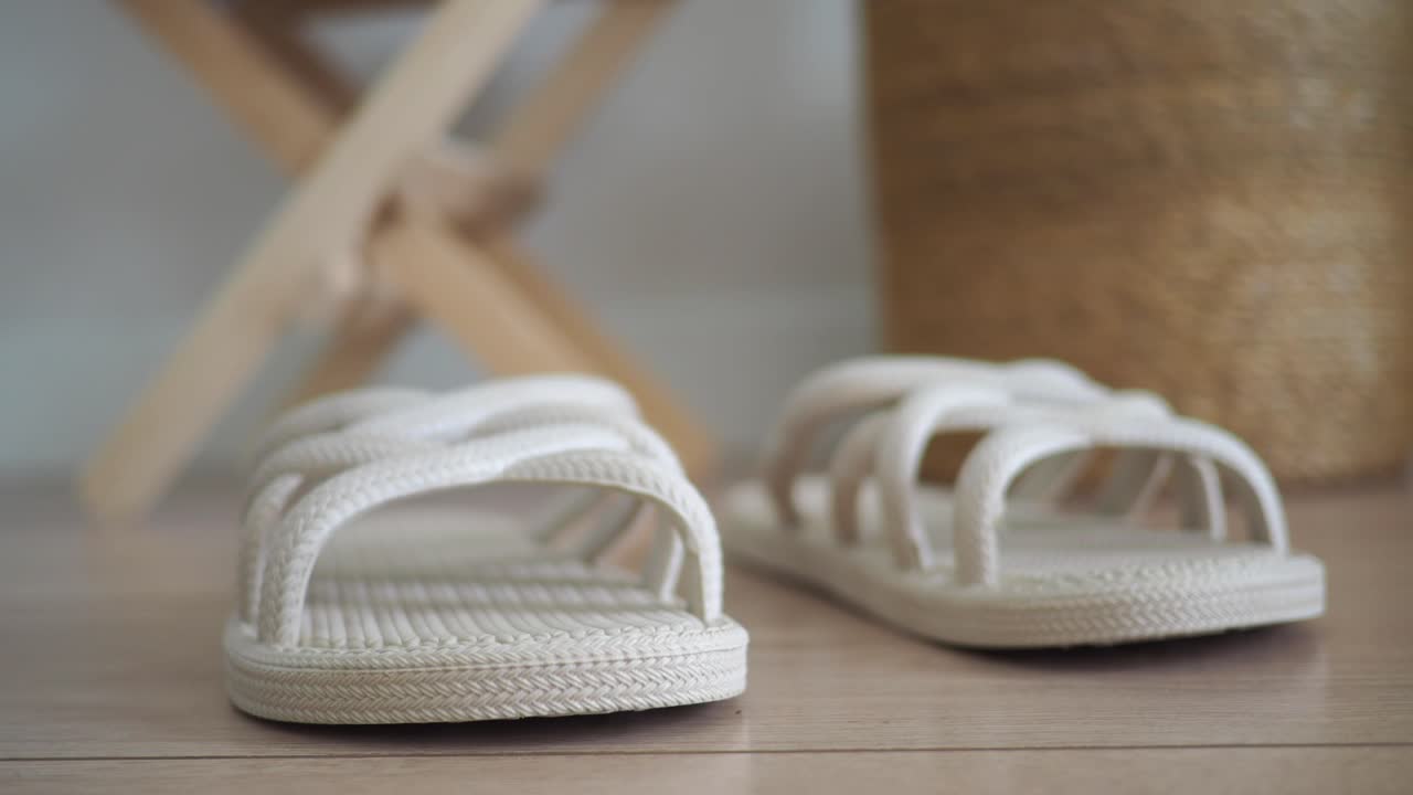 Et par hvite sandaler som hviler på et tregulv.