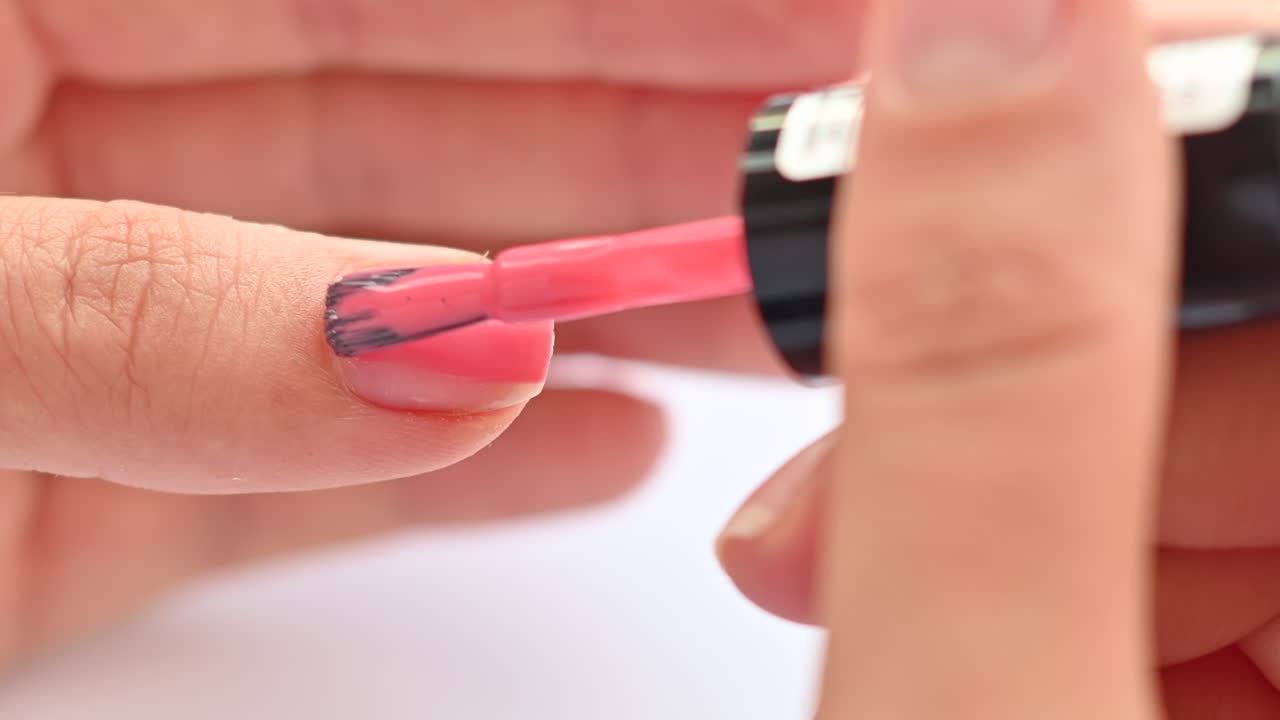 Mujer pintándose las uñas con esmalte de uñas rosa