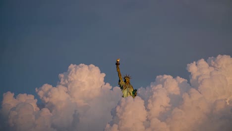 statue of liberty above the clouds at sunset