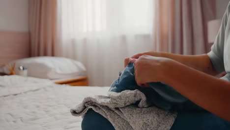 hands folding laundry on a bed in a bedroom