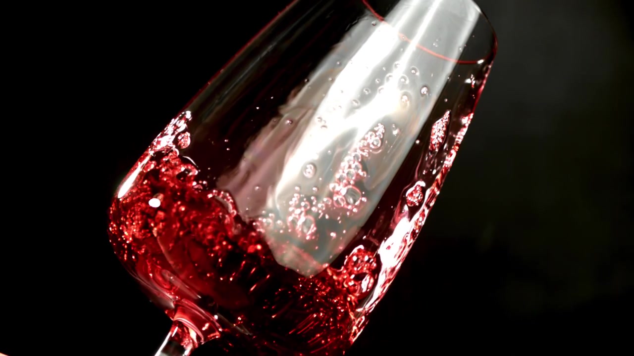 Vertido de vino tinto a cámara lenta en una copa inclinada