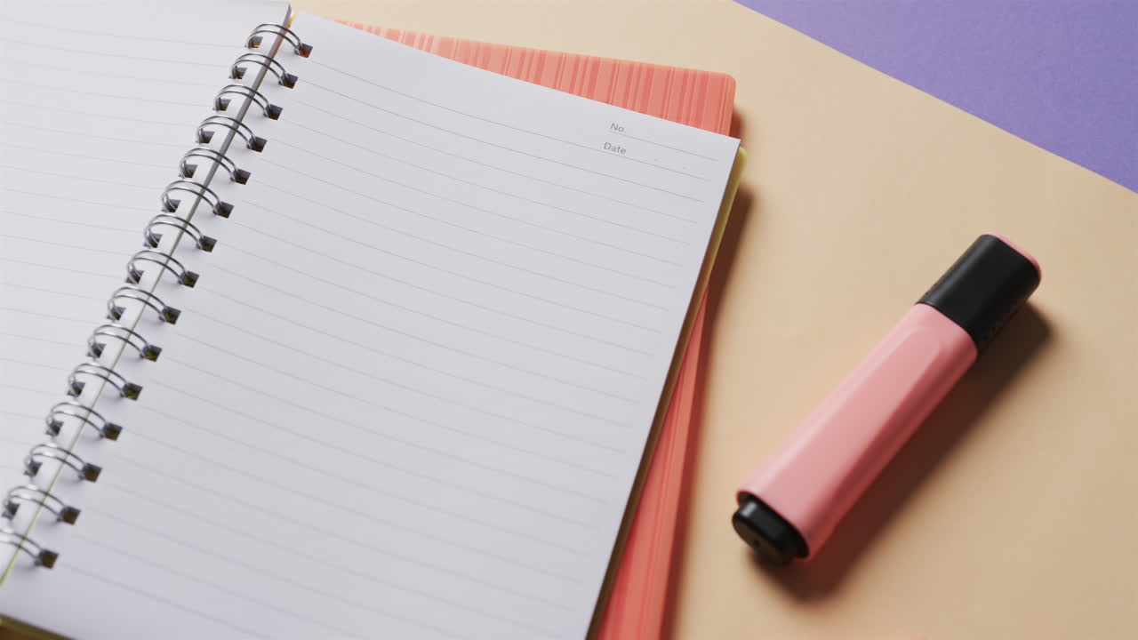 primer plano de un cuaderno abierto con papelería escolar en fondo beige y azul, en cámara lenta