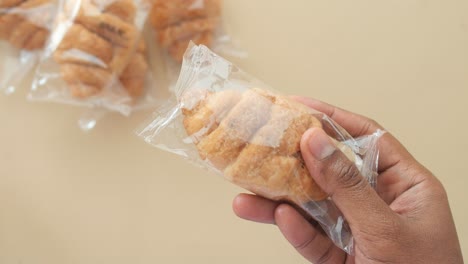 close-up of a hand holding a freshly baked croissant