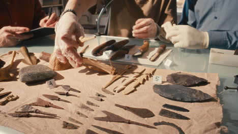 close-up of archaeology team discussing artifacts at table in laboratory