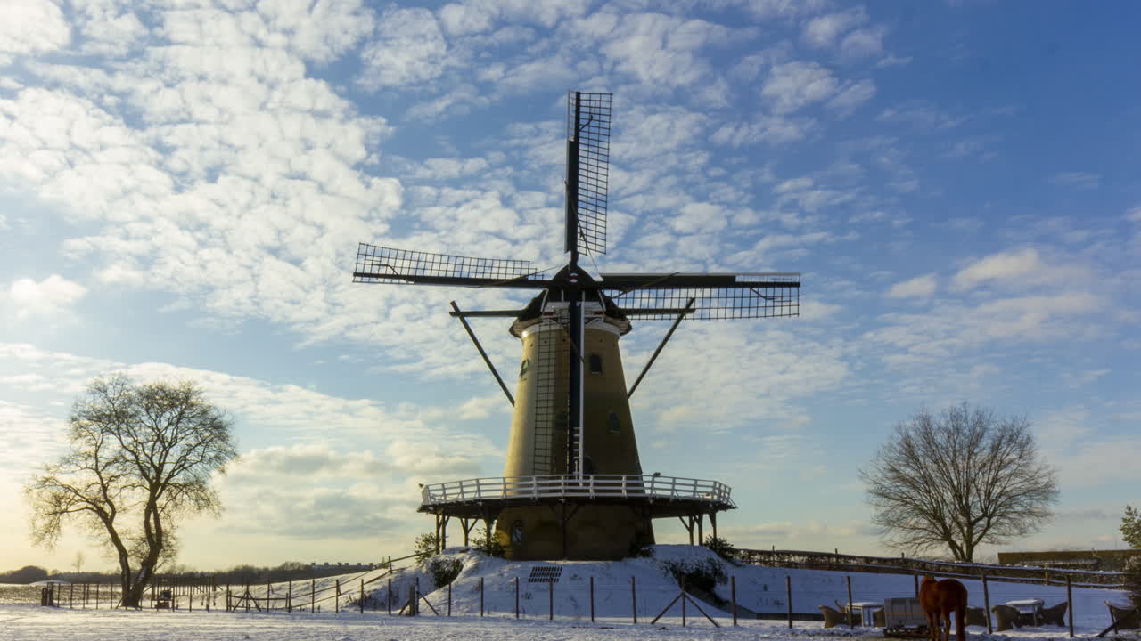 lapso de tiempo de las nubes que pasan sobre el molino de viento tradicional en el hermoso paisaje rural de invierno blanco - cultivo