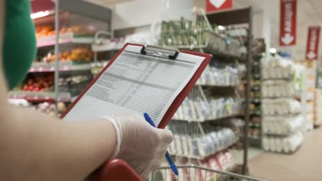 manos de mujer con guantes de protección mientras revisa la lista de compras en un centro comercial. atención médica y prevención de enfermedades por coronavirus, covid19