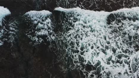 Spectacular-aerial-straight-down-view-of-giant-ocean-waves-crashing-and-foaming-with-rocky-coral-reef-landform,-seascape-at-Xiaoliuqiu-Lambai-Island,-Pingtung-county,-Taiwan