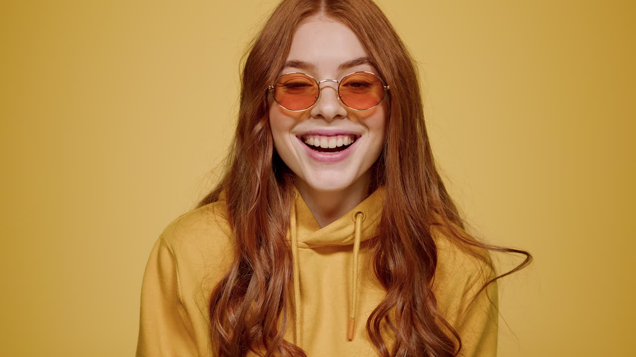 mujer eufórica haciendo un gesto de mano en el interior. chica actuando sobre un fondo naranja