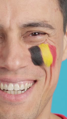 man with a belgian flag painted on the face smiling