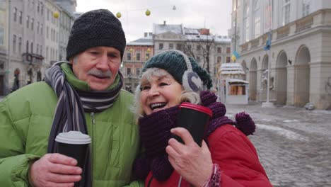 esposa mayor marido turistas bebiendo de tazas, disfrutando de té caliente en la calle central de la ciudad