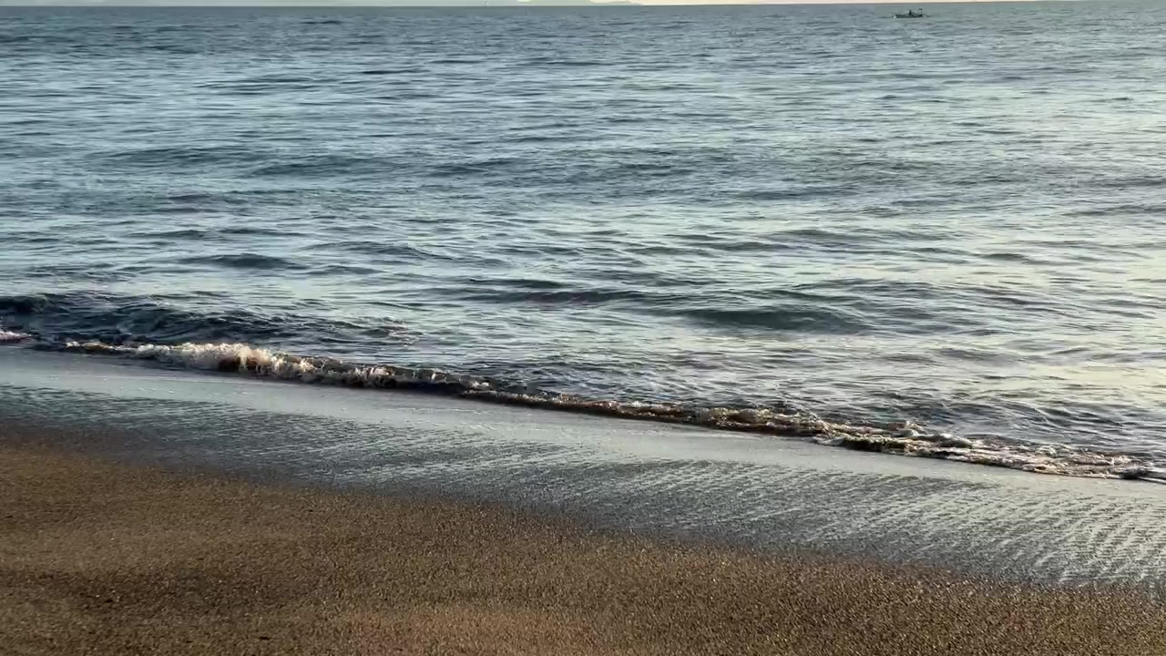 Blide havbølger skvulper på en sandstrand