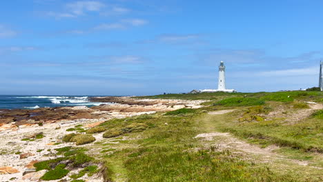 Cape-St-Francis-lighthouse-South-Africa-stunning-beautiful-summer-day-lush-green-beach-landscape-South-Africa-JBAY-Oyster-Garden-Route-wave-crashing-on-boulders-slow-motion-pan-to-the-left