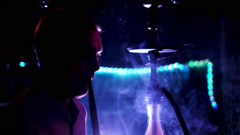 hombre fumando narguile en un club nocturno