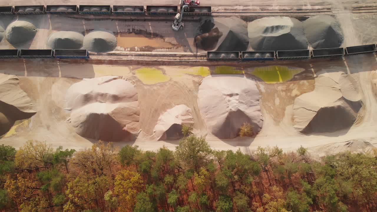 Aerial top down establishing shot of a big stacks of sand and gravel in a rail unloading siding