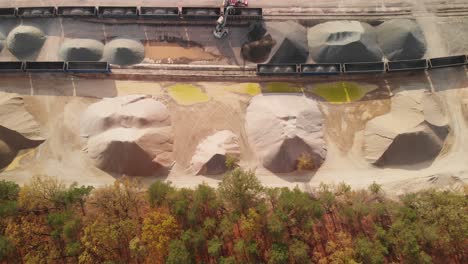 aerial top down establishing shot of a big stacks of sand and gravel in a rail unloading siding
